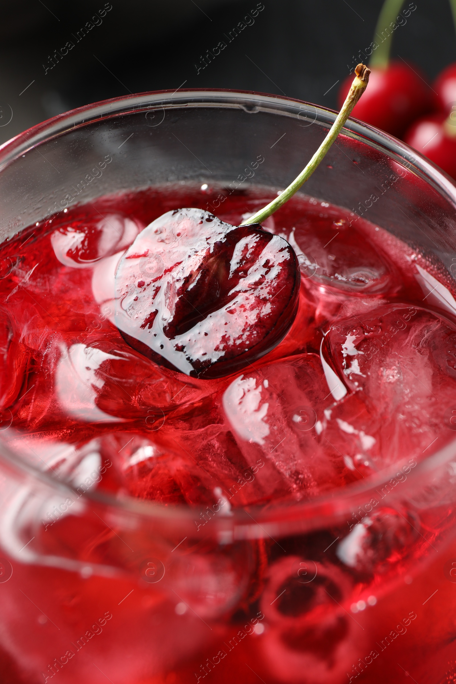 Tasty cherry soda with ice cubes and berry in glass on table, closeup Photo of Tasty cherry soda with ice cubes and berry in glass on table, closeup