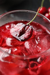 Photo of Tasty cherry soda with ice cubes and berry in glass on table, closeup