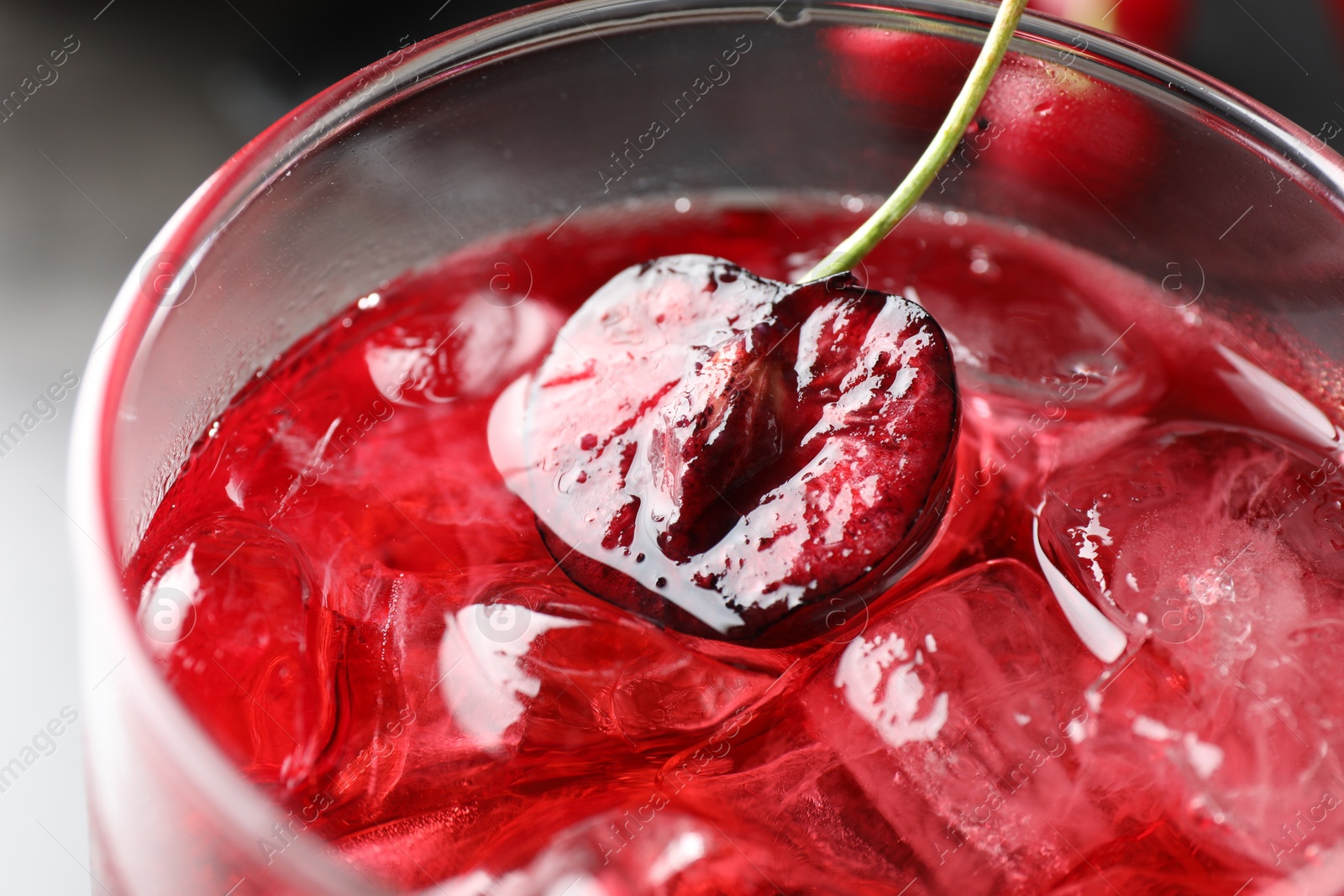 Tasty cherry soda with ice cubes and berry in glass on grey table, closeup Photo of Tasty cherry soda with ice cubes and berry in glass on grey table, closeup