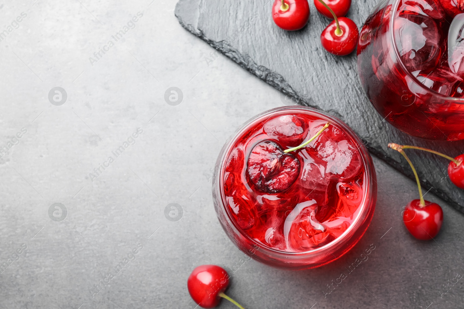 Tasty cherry soda with ice cubes and berries in glasses on grey table, flat lay Photo of Tasty cherry soda with ice cubes and berries in glasses on grey table, flat lay