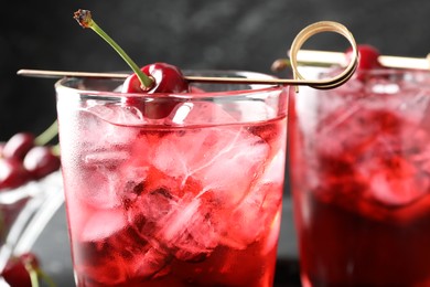 Photo of Tasty cherry soda with ice cubes and berries in glasses on table, closeup