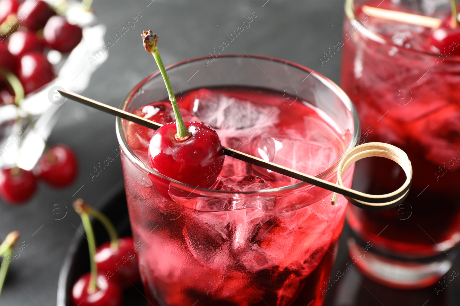 Tasty cherry soda with ice cubes and berries in glasses on grey table, closeup Photo of Tasty cherry soda with ice cubes and berries in glasses on grey table, closeup