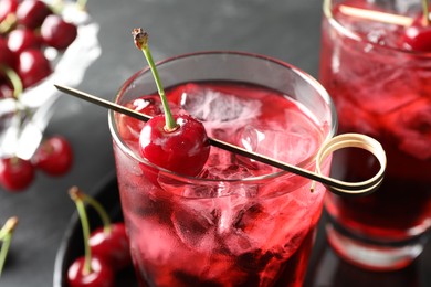 Photo of Tasty cherry soda with ice cubes and berries in glasses on grey table, closeup