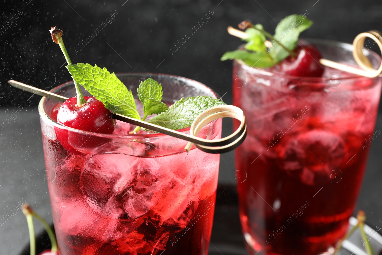 Tasty cherry soda with ice cubes, berries and mint in glasses on table, closeup Photo of Tasty cherry soda with ice cubes, berries and mint in glasses on table, closeup