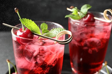Photo of Tasty cherry soda with ice cubes, berries and mint in glasses on table, closeup