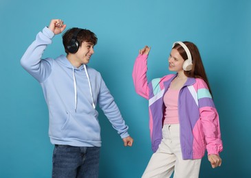 Photo of Teenage girl and boy with headphones dancing on light blue background