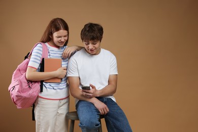 Photo of Teenagers with backpack, books and smartphone on brown background. Space for text