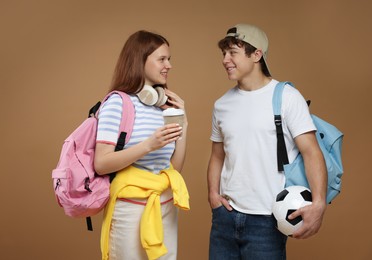 Photo of Teenagers with backpacks, soccer ball and drink on brown background