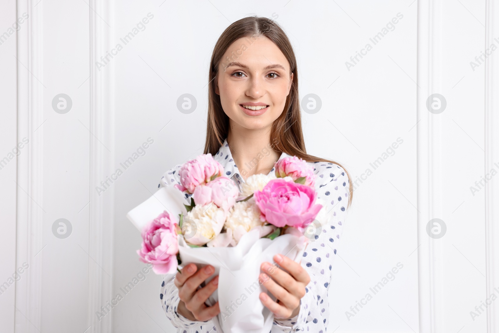 Photo of Woman with beautiful bouquet of peonies near white wall indoors