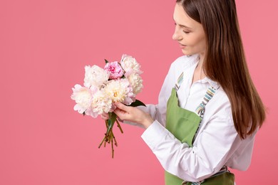 Photo of Florist with beautiful peonies on pink background, space for text