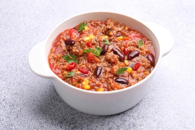 Photo of Tasty chili con carne in bowl on grey table, closeup