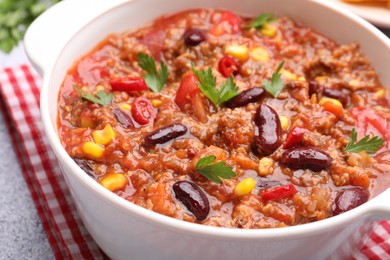 Photo of Tasty chili con carne in bowl on grey table, closeup