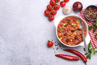 Photo of Tasty chili con carne in bowl and ingredients on grey table, flat lay. Space for text