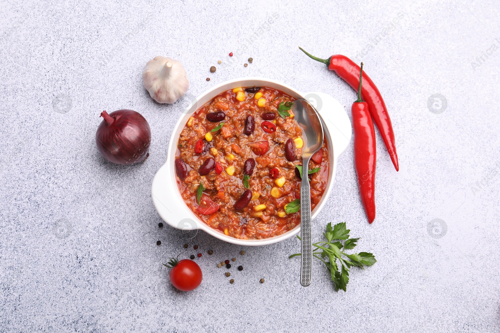 Tasty chili con carne in bowl and ingredients on grey table, flat lay Photo of Tasty chili con carne in bowl and ingredients on grey table, flat lay