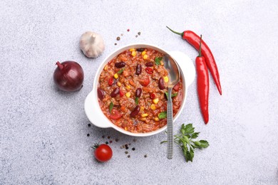 Photo of Tasty chili con carne in bowl and ingredients on grey table, flat lay