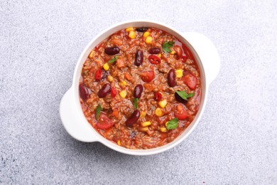 Photo of Tasty chili con carne in bowl on grey table, top view