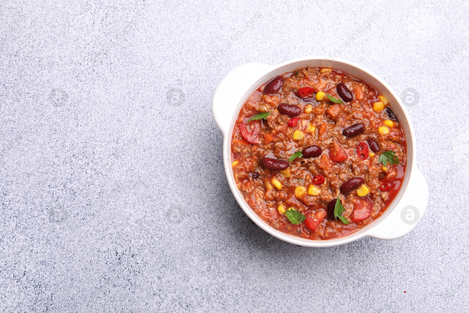 Tasty chili con carne in bowl on grey table, top view. Space for text Photo of Tasty chili con carne in bowl on grey table, top view. Space for text