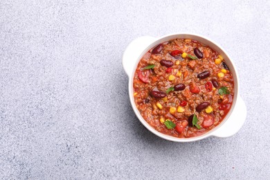 Photo of Tasty chili con carne in bowl on grey table, top view. Space for text