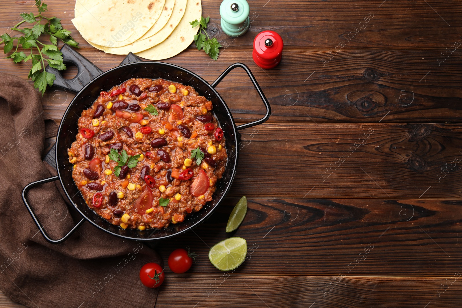Tasty chili con carne in baking dish and flatbread on wooden table, flat lay. Space for text Photo of Tasty chili con carne in baking dish and flatbread on wooden table, flat lay. Space for text
