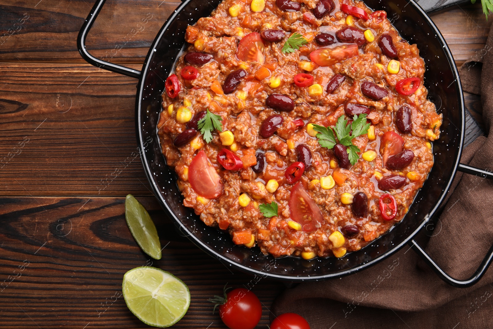 Tasty chili con carne in baking dish on wooden table, flat lay Photo of Tasty chili con carne in baking dish on wooden table, flat lay