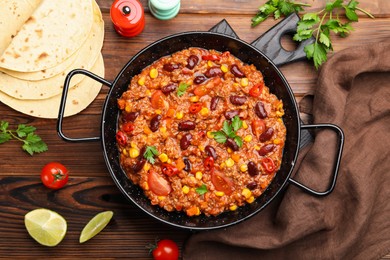 Photo of Tasty chili con carne in baking dish and flatbread on wooden table, flat lay