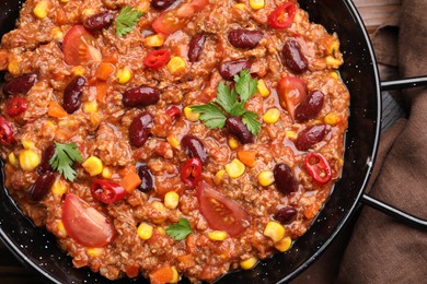 Photo of Tasty chili con carne in baking dish on wooden table, top view