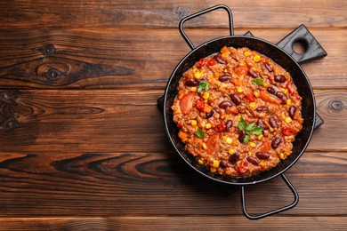 Photo of Tasty chili con carne in baking dish on wooden table, top view. Space for text