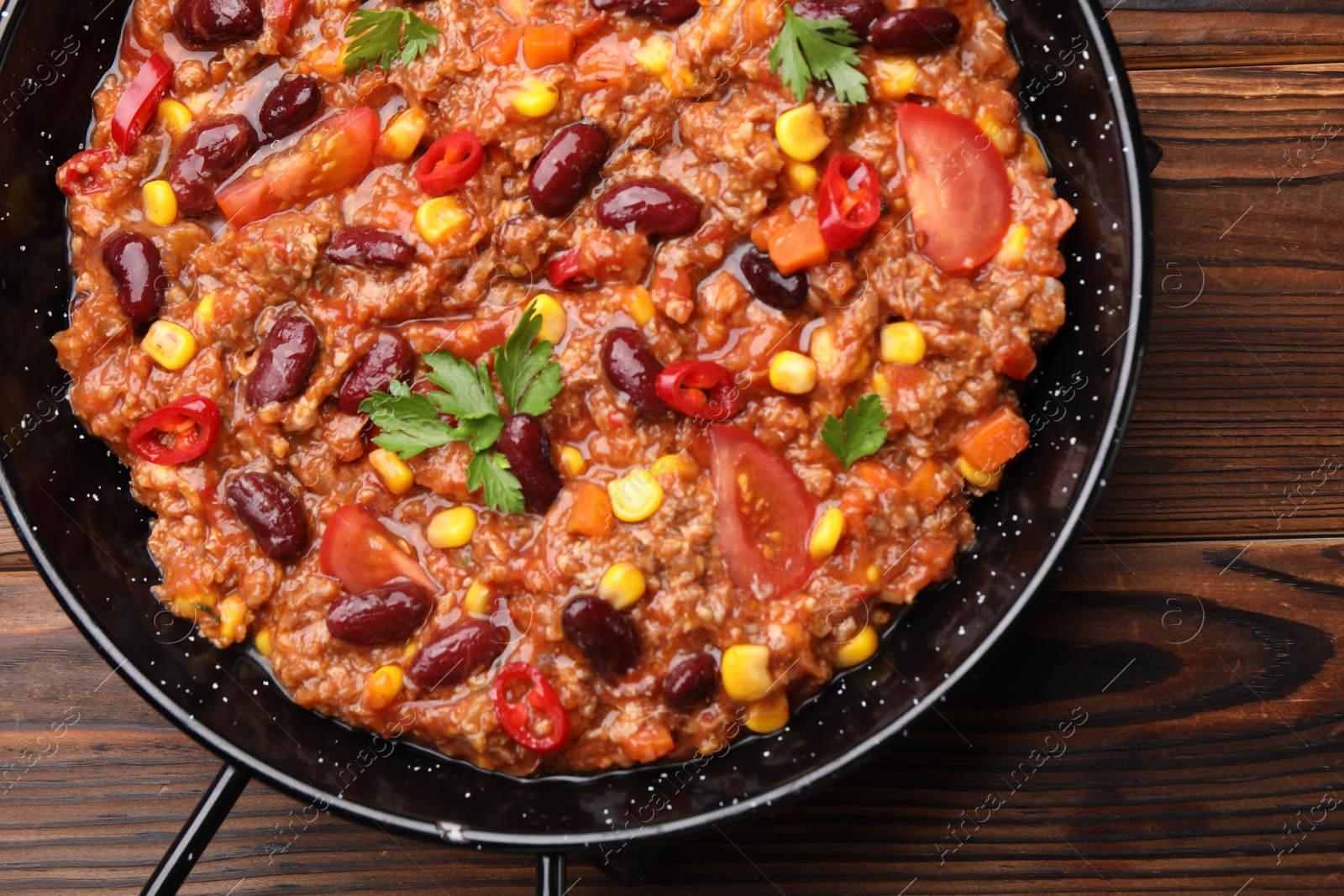 Tasty chili con carne in baking dish on wooden table, top view Photo of Tasty chili con carne in baking dish on wooden table, top view