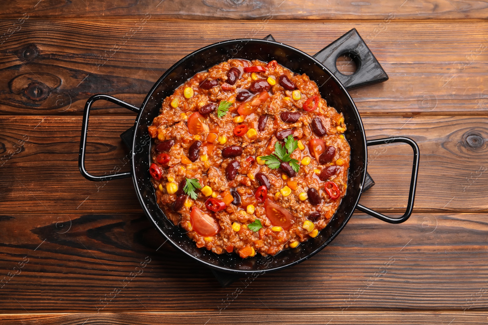 Tasty chili con carne in baking dish on wooden table, top view Photo of Tasty chili con carne in baking dish on wooden table, top view
