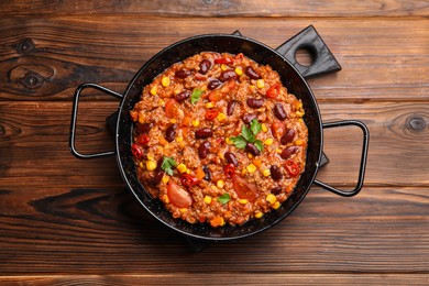 Photo of Tasty chili con carne in baking dish on wooden table, top view