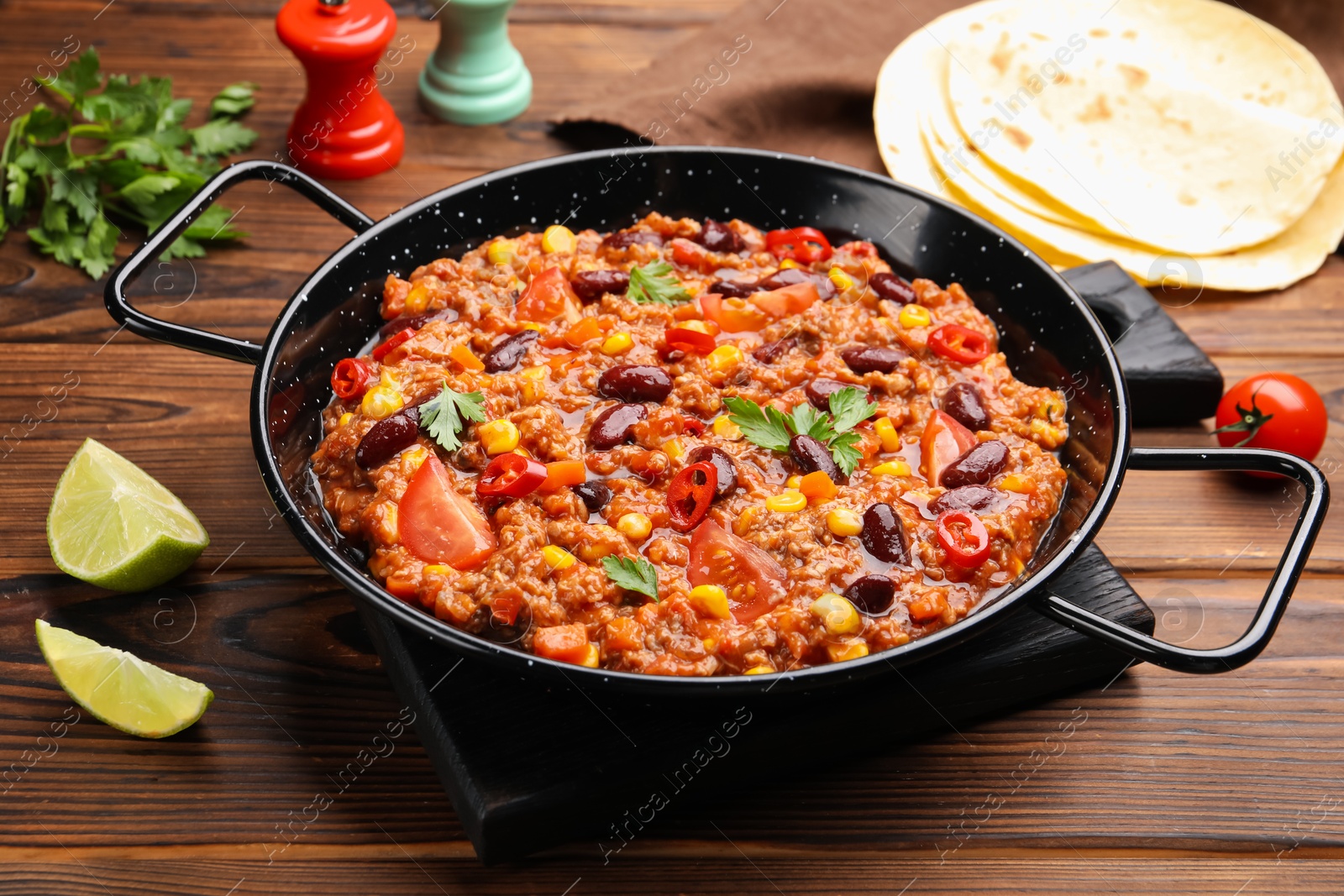 Tasty chili con carne in baking dish and flatbread on wooden table, closeup Photo of Tasty chili con carne in baking dish and flatbread on wooden table, closeup