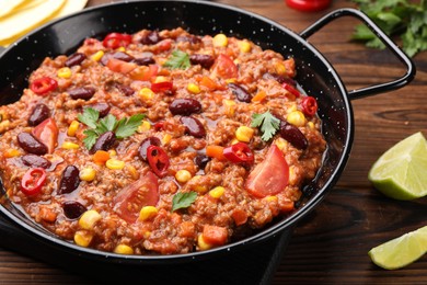 Photo of Tasty chili con carne in baking dish on wooden table, closeup