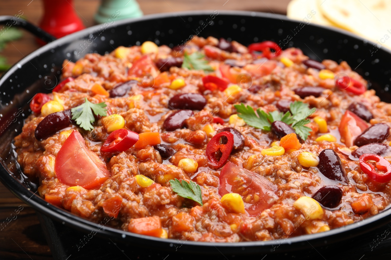 Tasty chili con carne in baking dish on wooden table, closeup Photo of Tasty chili con carne in baking dish on wooden table, closeup