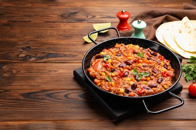 Photo of Tasty chili con carne in baking dish and flatbread on wooden table, closeup. Space for text