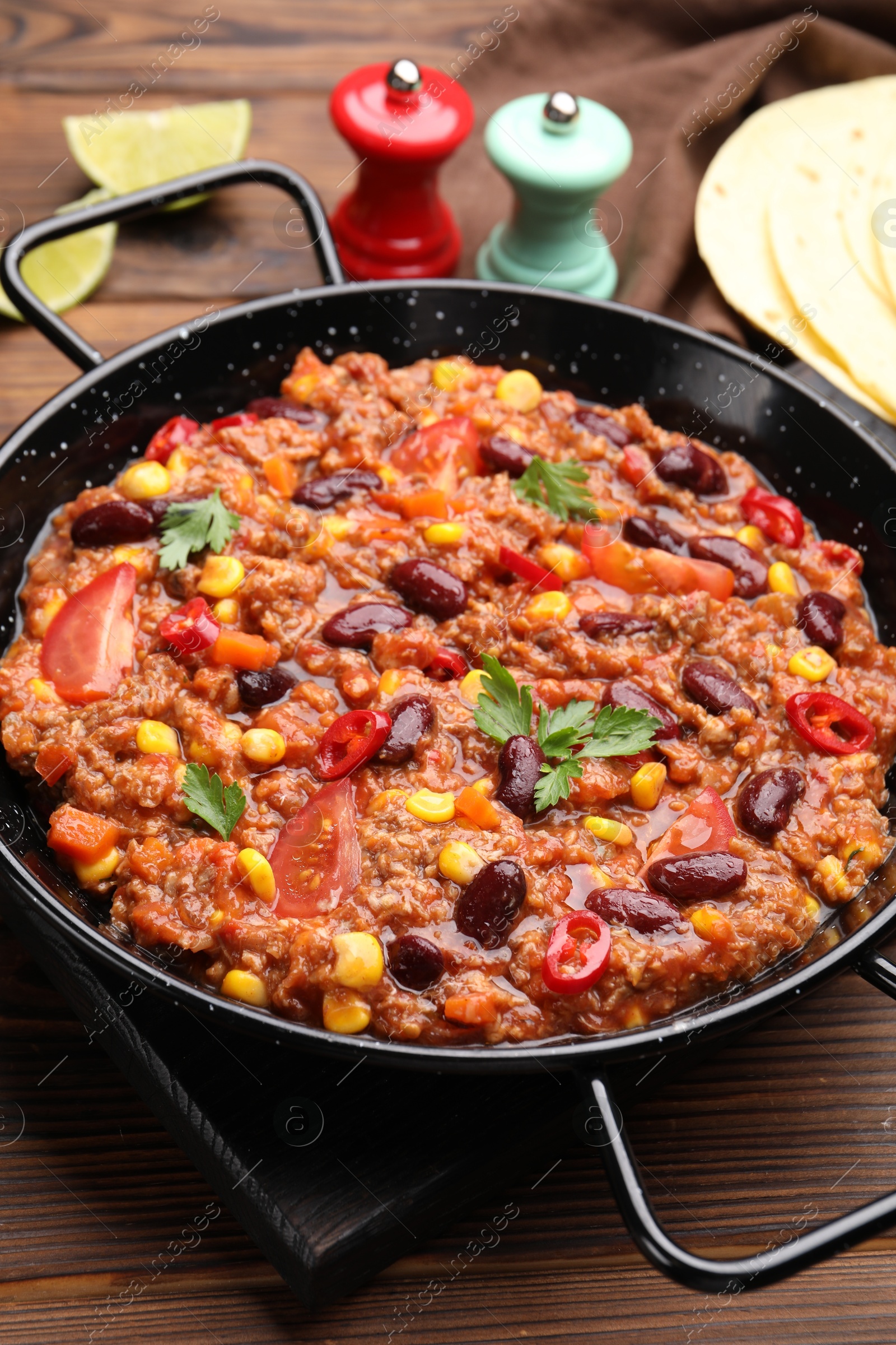 Tasty chili con carne in baking dish on wooden table, closeup Photo of Tasty chili con carne in baking dish on wooden table, closeup