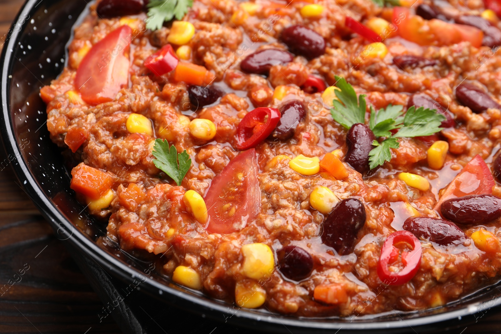 Tasty chili con carne in baking dish on wooden table, closeup Photo of Tasty chili con carne in baking dish on wooden table, closeup