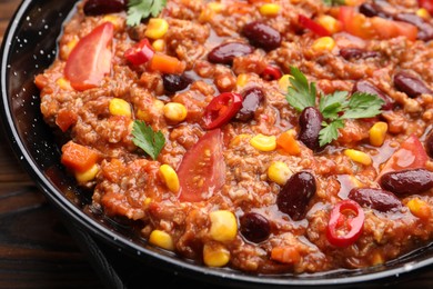 Photo of Tasty chili con carne in baking dish on wooden table, closeup