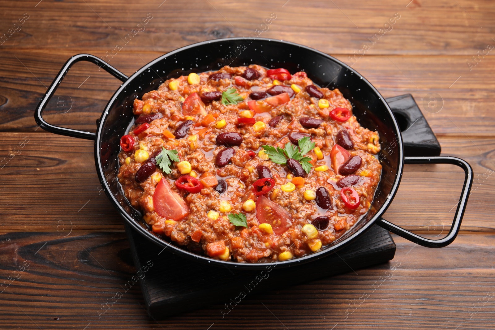 Tasty chili con carne in baking dish on wooden table, closeup Photo of Tasty chili con carne in baking dish on wooden table, closeup