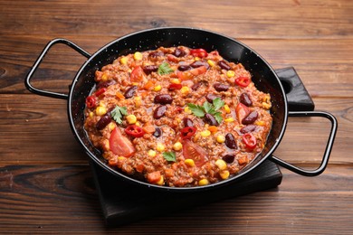 Photo of Tasty chili con carne in baking dish on wooden table, closeup