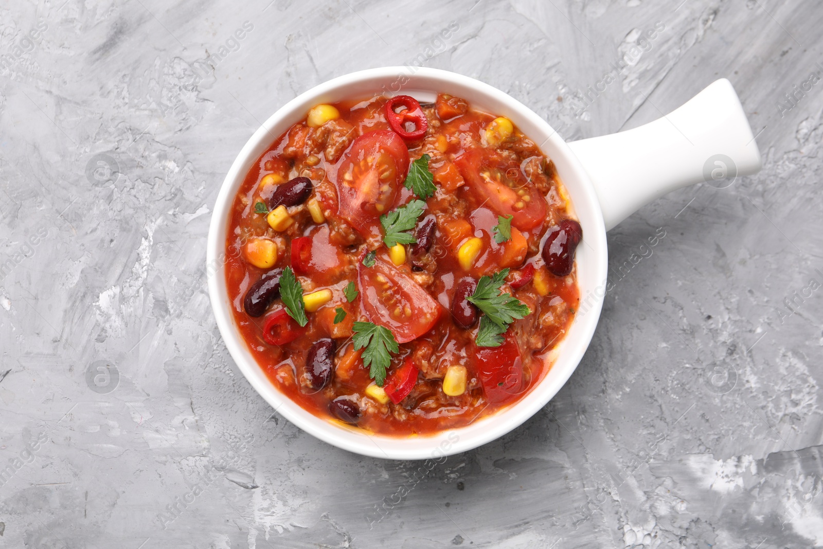 Tasty chili con carne in bowl on grey textured table, top view Photo of Tasty chili con carne in bowl on grey textured table, top view