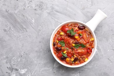 Photo of Tasty chili con carne in bowl on grey textured table, top view. Space for text