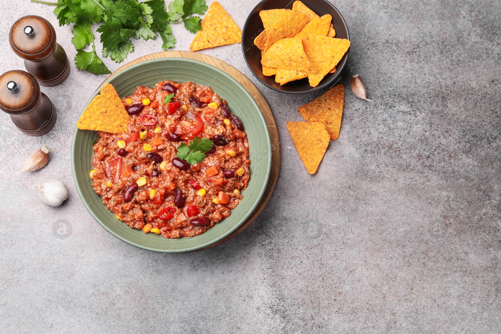 Tasty chili con carne in bowl and nachos on grey table, flat lay. Space for text Photo of Tasty chili con carne in bowl and nachos on grey table, flat lay. Space for text