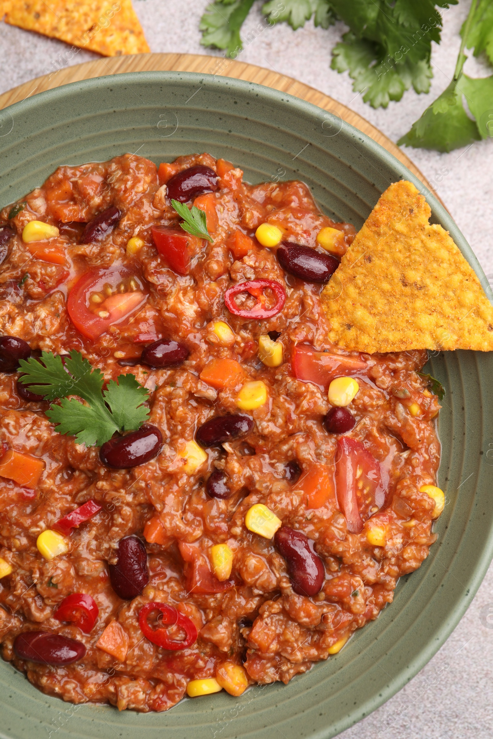 Tasty chili con carne in bowl and nachos on grey table, flat lay Photo of Tasty chili con carne in bowl and nachos on grey table, flat lay
