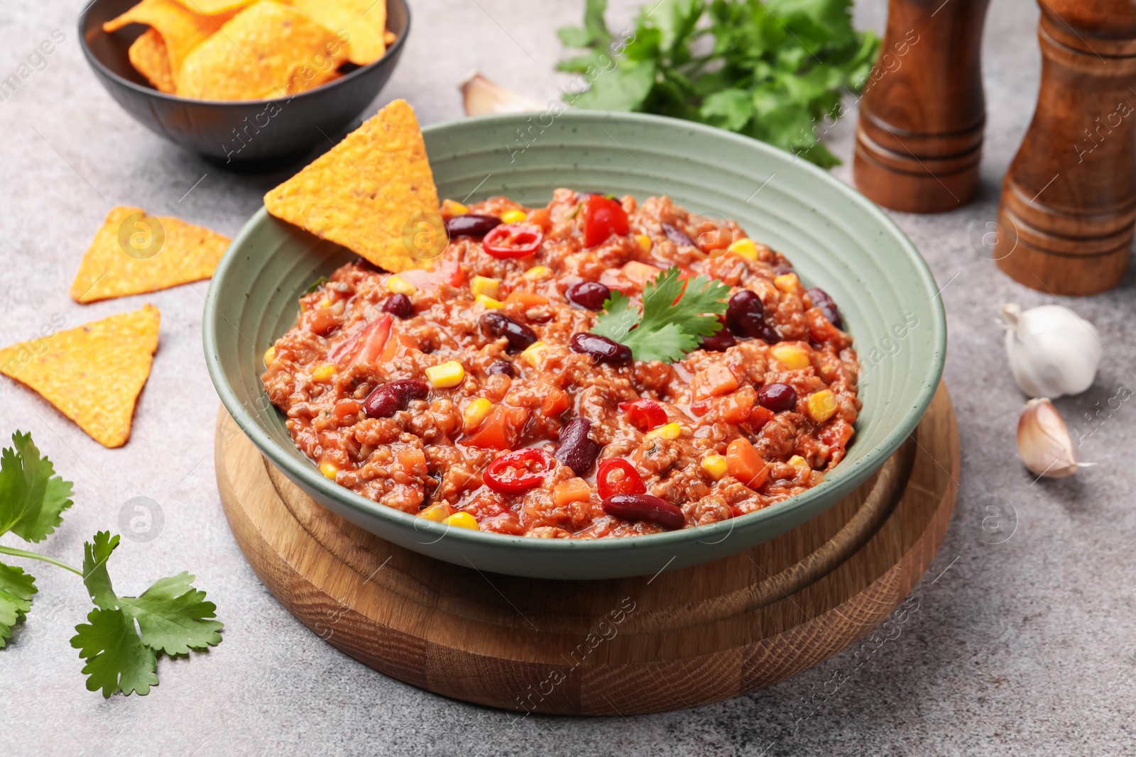 Tasty chili con carne in bowl and nachos on grey table, closeup Photo of Tasty chili con carne in bowl and nachos on grey table, closeup