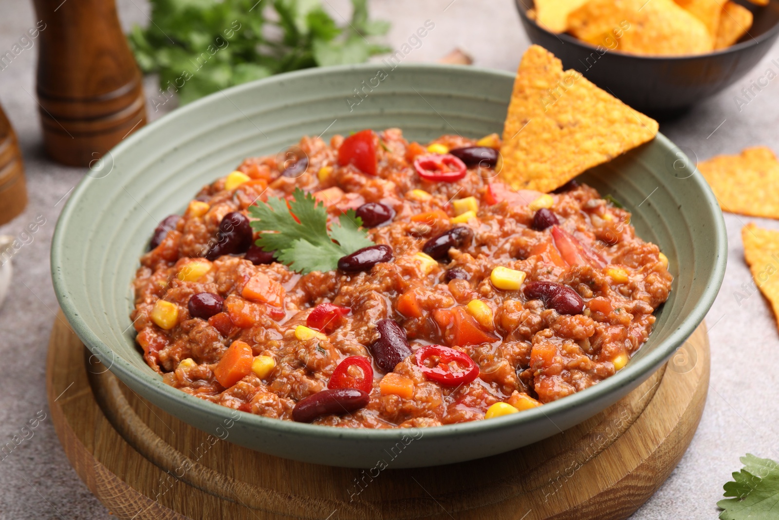 Tasty chili con carne in bowl and nachos on grey table, closeup Photo of Tasty chili con carne in bowl and nachos on grey table, closeup