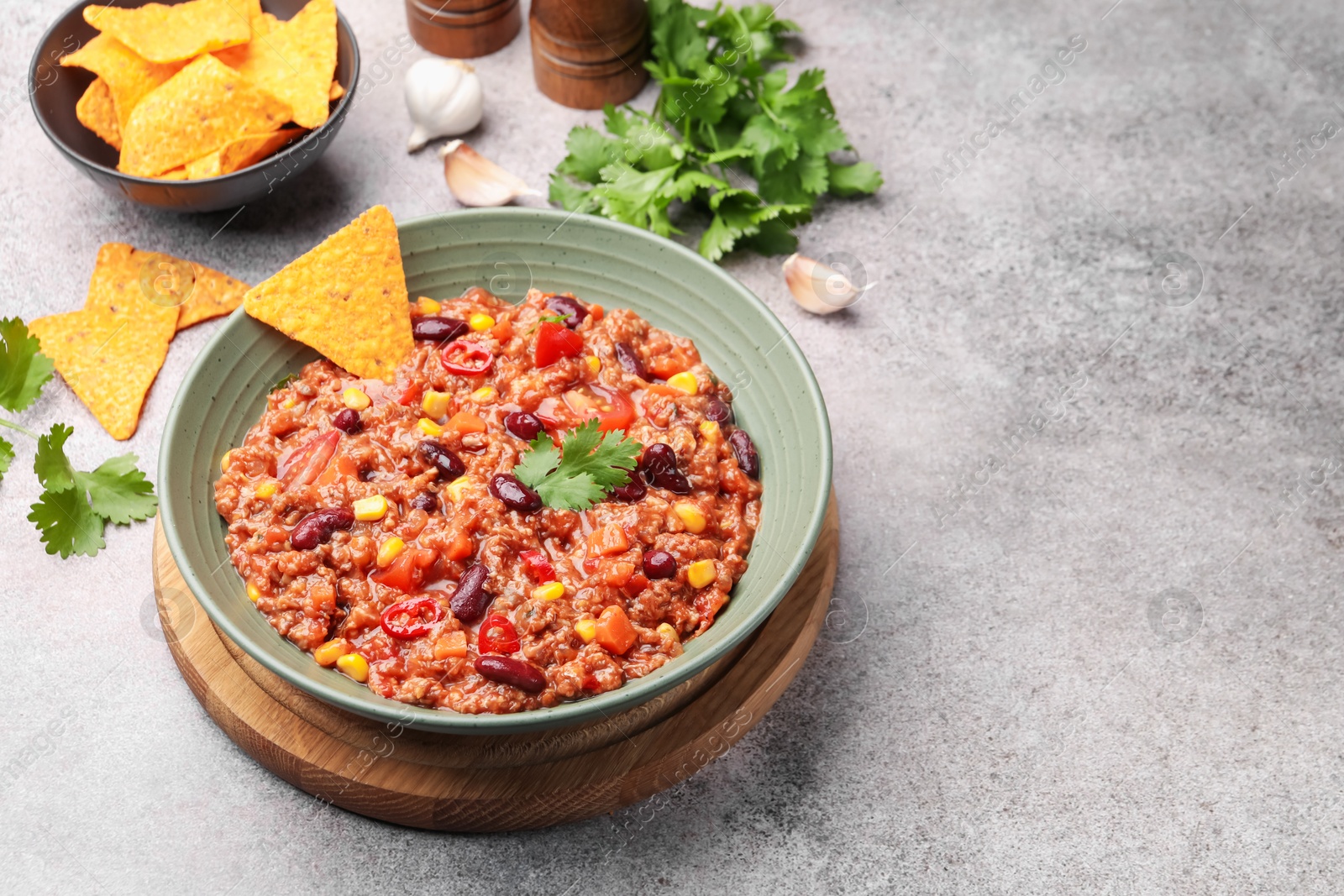 Tasty chili con carne in bowl and nachos on grey table, closeup. Space for text Photo of Tasty chili con carne in bowl and nachos on grey table, closeup. Space for text