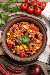Photo of Tasty chili con carne in bowl and ingredients on wooden table, flat lay