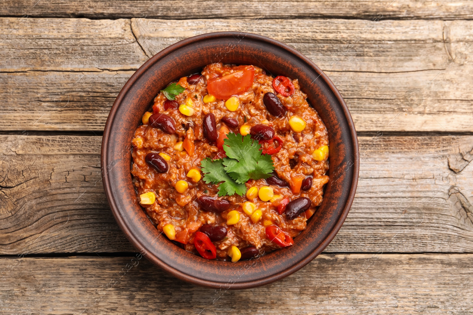 Tasty chili con carne in bowl on wooden table, top view Photo of Tasty chili con carne in bowl on wooden table, top view