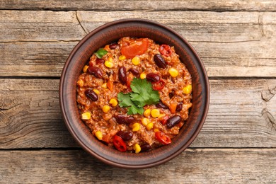 Photo of Tasty chili con carne in bowl on wooden table, top view