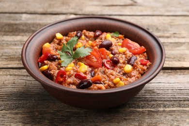 Photo of Tasty chili con carne in bowl on wooden table, closeup